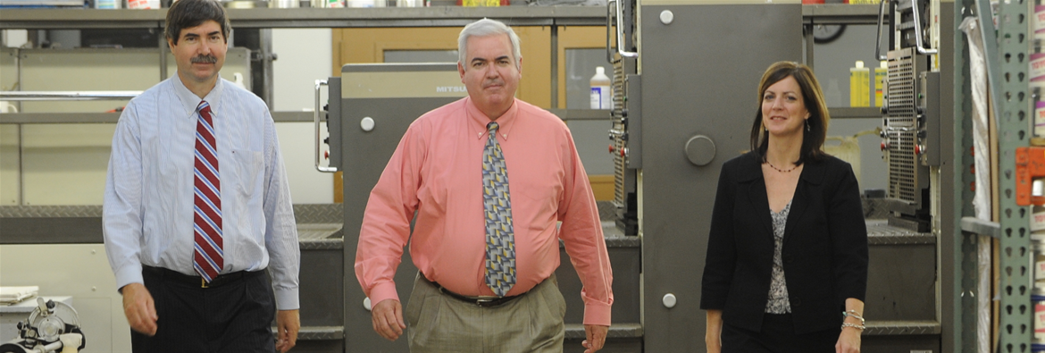 Steve, Mary and Kevin Richards walk toward camera inside of building.